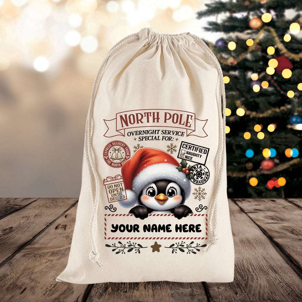 Personalized Christmas gift bag with penguin design and festive text on a wooden surface with a blurred Christmas tree in the background.