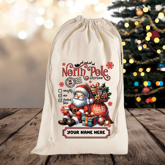 Decorative Christmas sack with Santa Claus design and 'North Pole Express' text on a wooden surface with a blurred Christmas tree in the background.